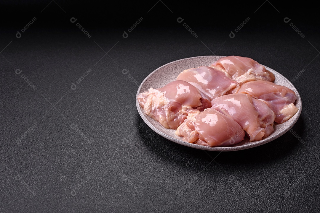 A imagem mostra sobrecoxas de frango cruas em um prato azul. A sobrecoxa é a parte superior da perna do frango