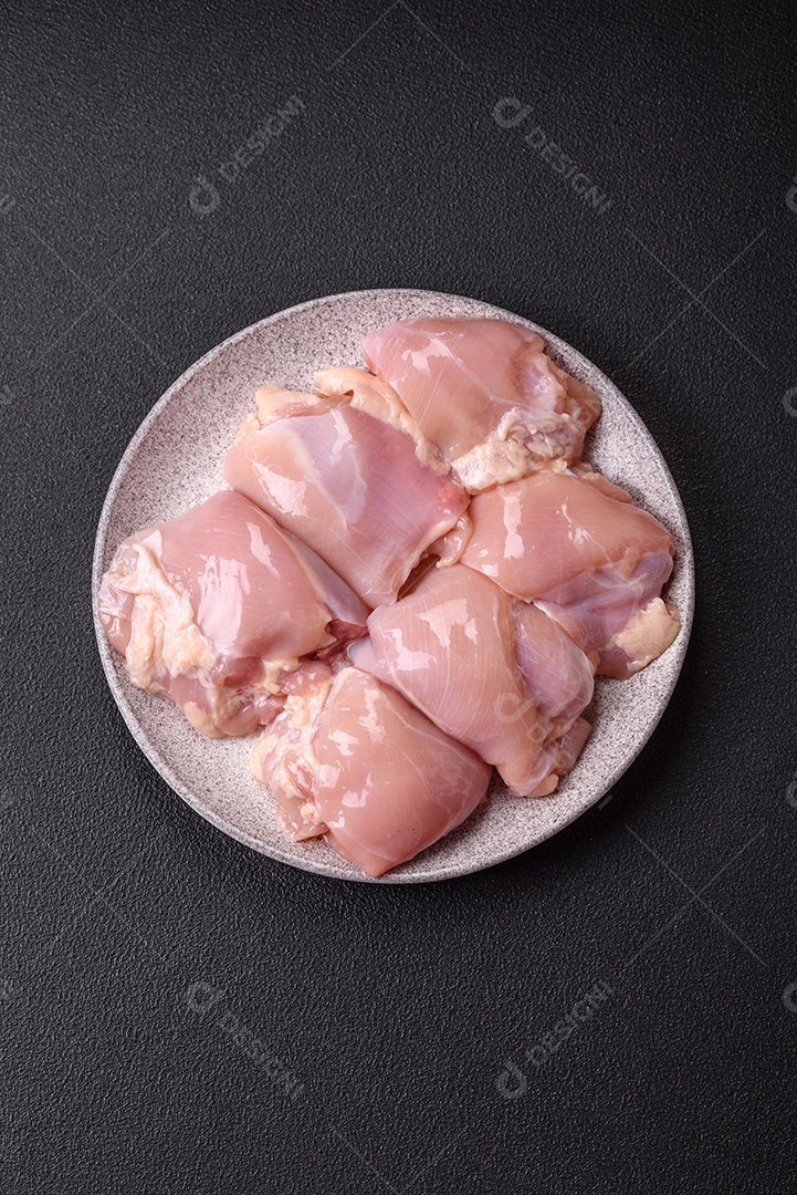 A imagem mostra sobrecoxas de frango cruas em um prato azul. A sobrecoxa é a parte superior da perna do frango