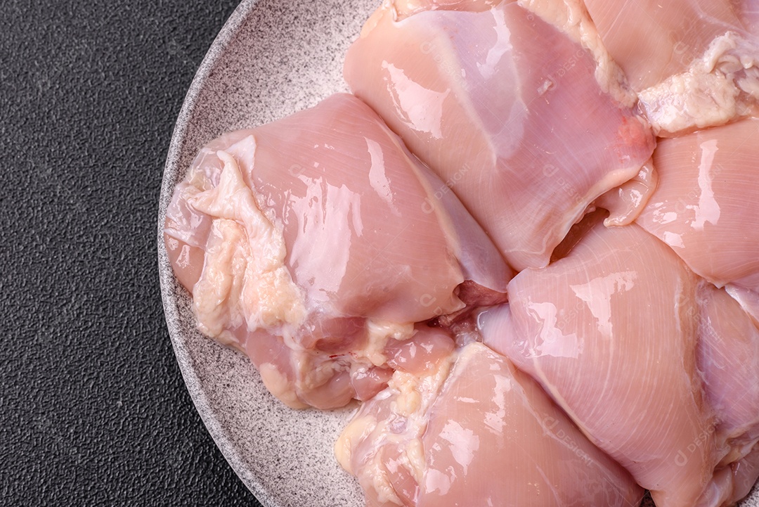 A imagem mostra sobrecoxas de frango cruas em um prato. A sobrecoxa é a parte superior da perna do frango