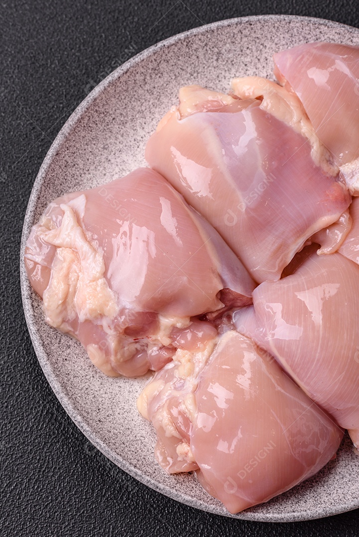 A imagem mostra sobrecoxas de frango cruas em um prato azul. A sobrecoxa é a parte superior da perna do frango