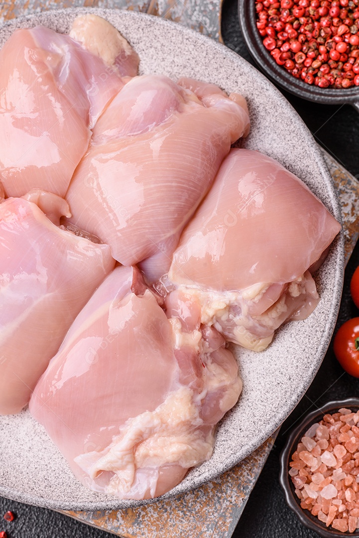 A imagem mostra sobrecoxas de frango cruas em um prato azul. A sobrecoxa é a parte superior da perna do frango