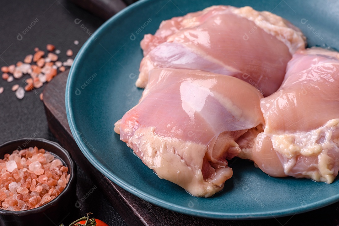 A imagem mostra sobrecoxas de frango cruas em um prato azul. A sobrecoxa é a parte superior da perna do frango