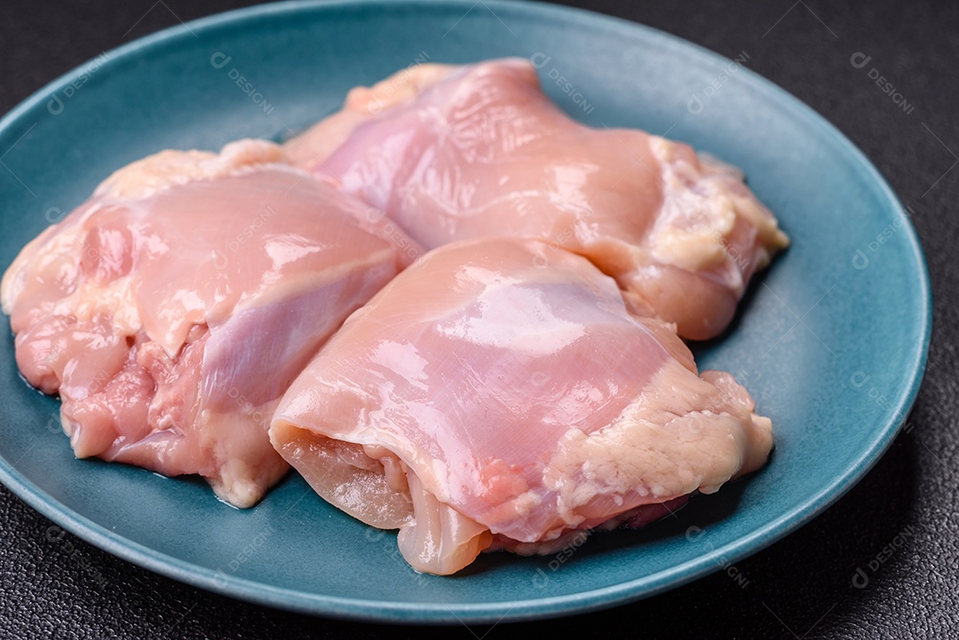 A imagem mostra sobrecoxas de frango cruas em um prato azul. A sobrecoxa é a parte superior da perna do frango