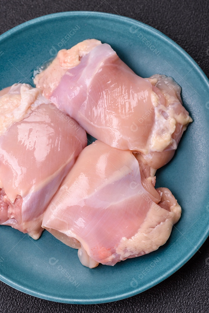 A imagem mostra sobrecoxas de frango cruas em um prato azul. A sobrecoxa é a parte superior da perna do frango