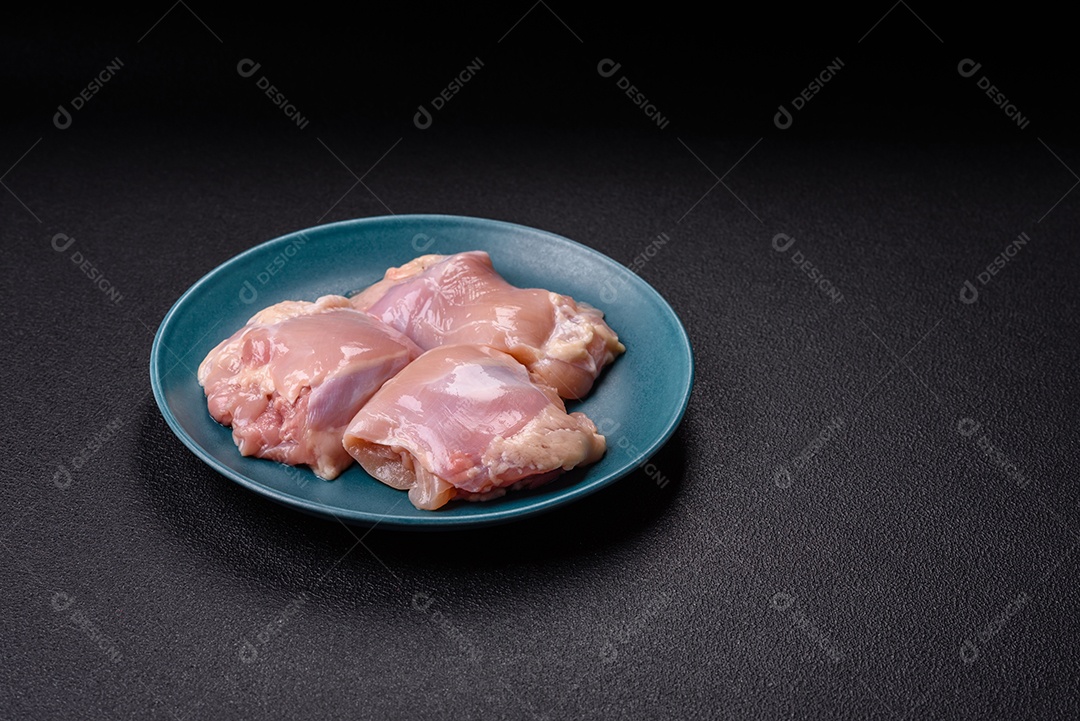 A imagem mostra sobrecoxas de frango cruas em um prato azul. A sobrecoxa é a parte superior da perna do frango