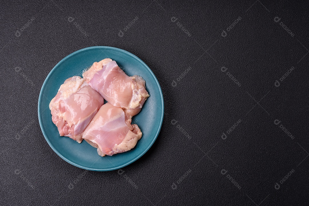 A imagem mostra sobrecoxas de frango cruas em um prato azul. A sobrecoxa é a parte superior da perna do frango