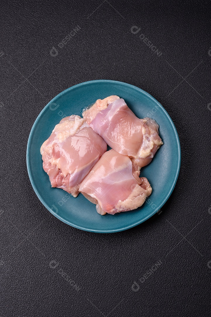 A imagem mostra sobrecoxas de frango cruas em um prato azul. A sobrecoxa é a parte superior da perna do frango