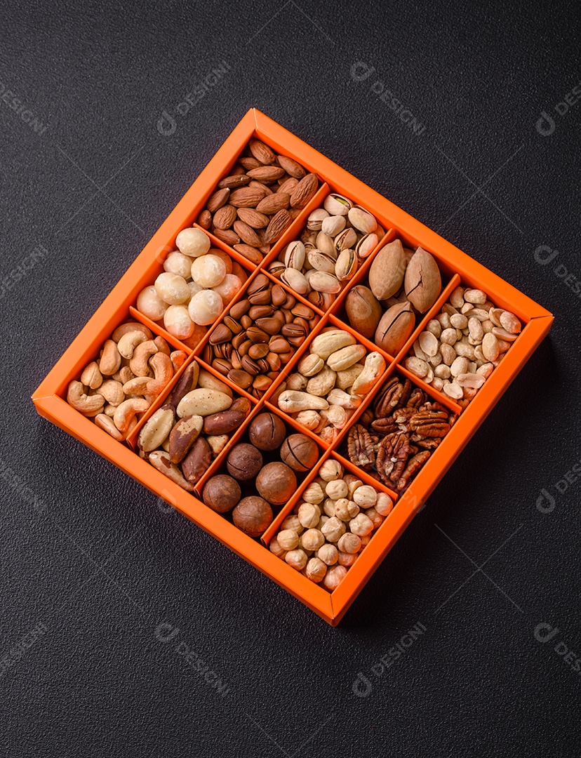 Imagem mostra uma variedade de oleaginosas, comumente chamadas de castanhas e nozes, em uma caixa dividida em compartimentos.