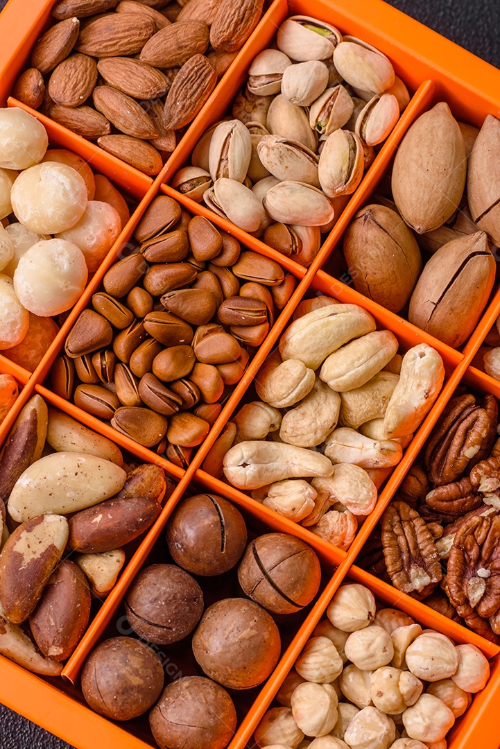 Imagem mostra uma variedade de oleaginosas, comumente chamadas de castanhas e nozes, em uma caixa dividida em compartimentos.