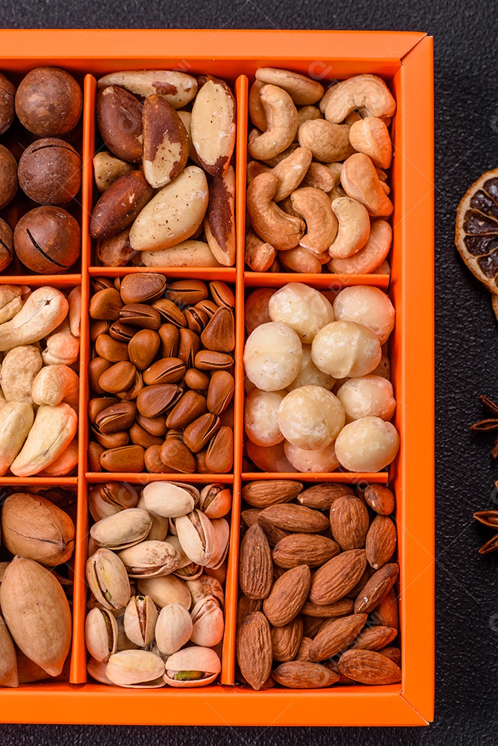 Imagem mostra uma variedade de oleaginosas, comumente chamadas de castanhas e nozes, em uma caixa dividida em compartimentos.