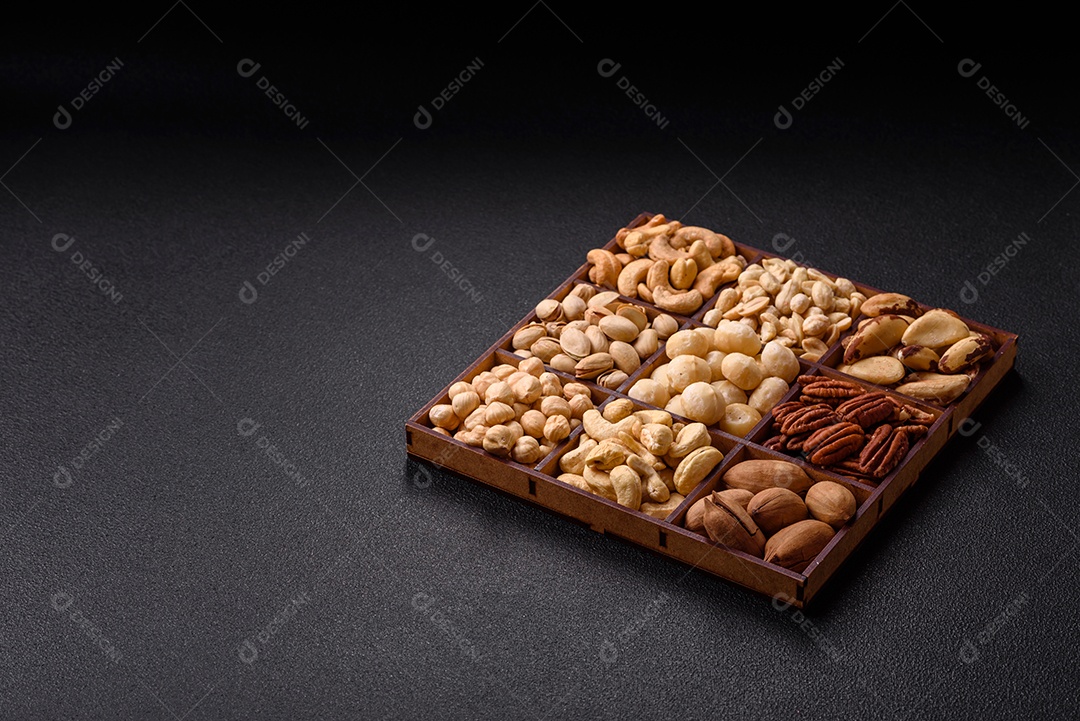 Imagem mostra uma variedade de oleaginosas, comumente chamadas de castanhas e nozes, em uma caixa dividida em compartimentos.