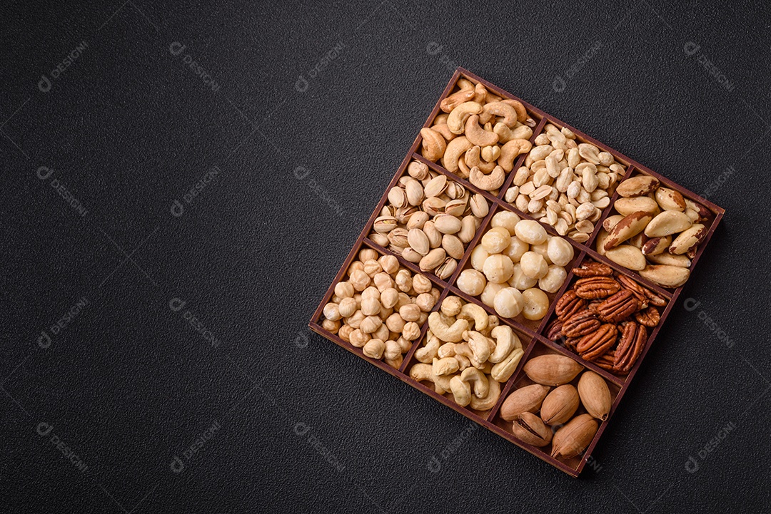 Imagem mostra uma variedade de oleaginosas, comumente chamadas de castanhas e nozes, em uma caixa dividida em compartimentos.