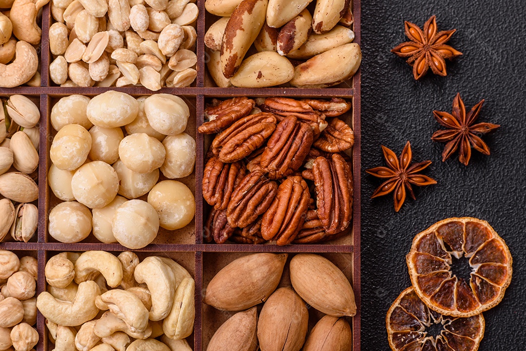 Imagem mostra uma variedade de oleaginosas, comumente chamadas de castanhas e nozes, em uma caixa dividida em compartimentos.