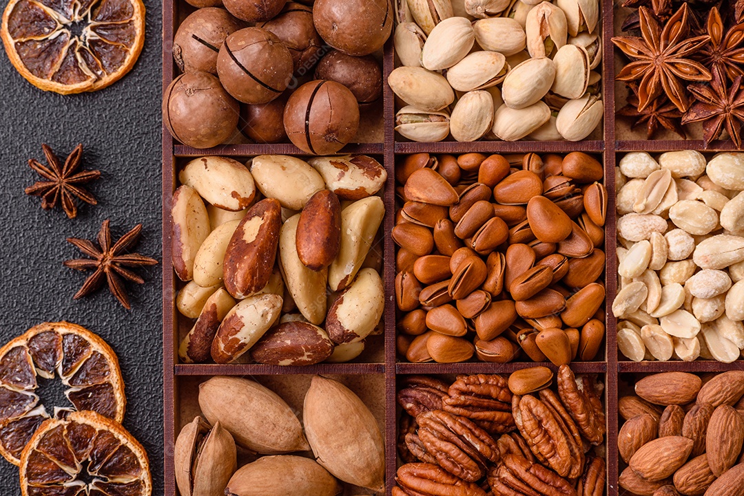 Imagem mostra uma variedade de oleaginosas, comumente chamadas de castanhas e nozes, em uma caixa dividida em compartimentos.