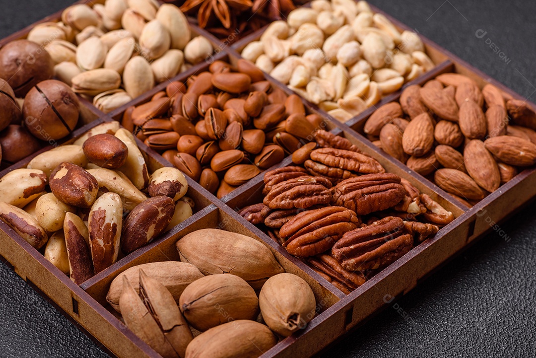Imagem mostra uma variedade de oleaginosas, comumente chamadas de castanhas e nozes, em uma caixa dividida em compartimentos.