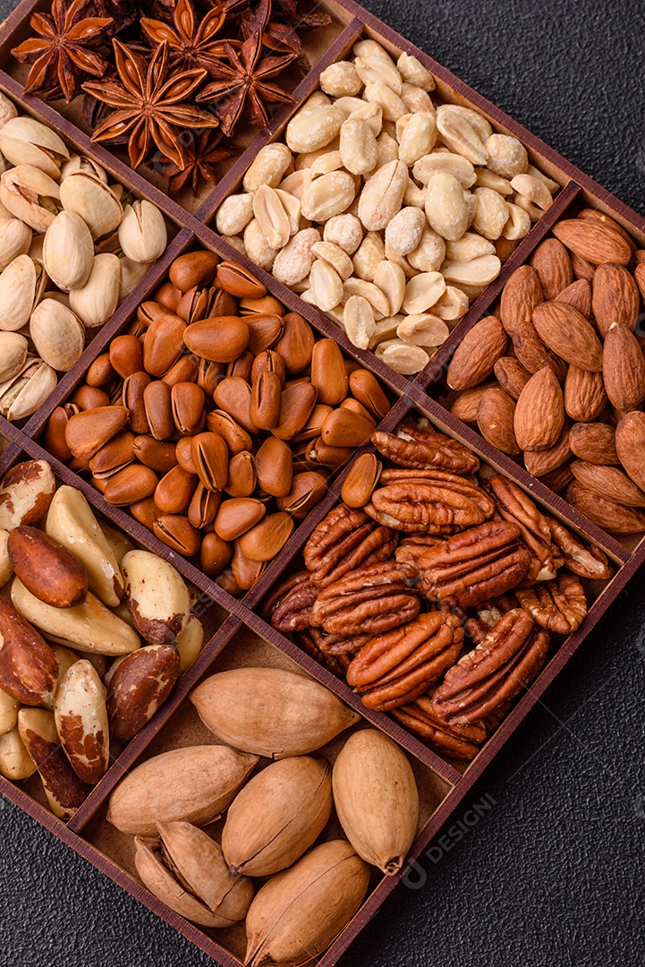 Imagem mostra uma variedade de oleaginosas, comumente chamadas de castanhas e nozes, em uma caixa dividida em compartimentos.