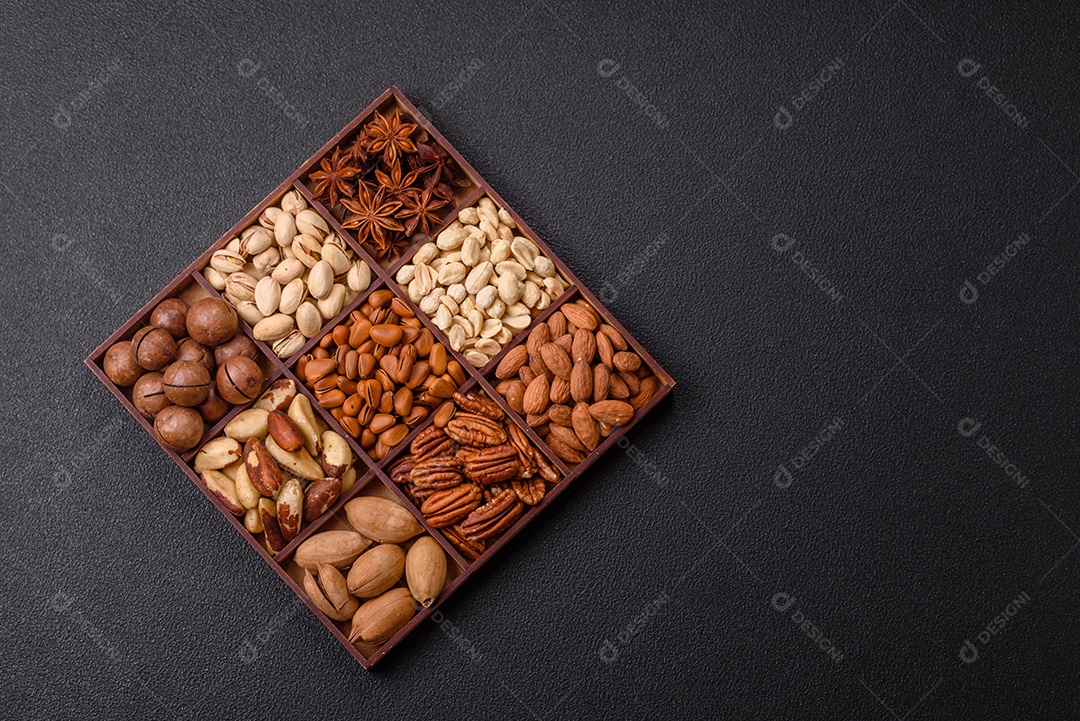 Imagem mostra uma variedade de oleaginosas, comumente chamadas de castanhas e nozes, em uma caixa dividida em compartimentos.