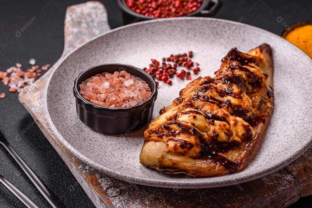 O prato na imagem parece ser um filé de cavala grelhado, servido com um molho e pimenta rosa.