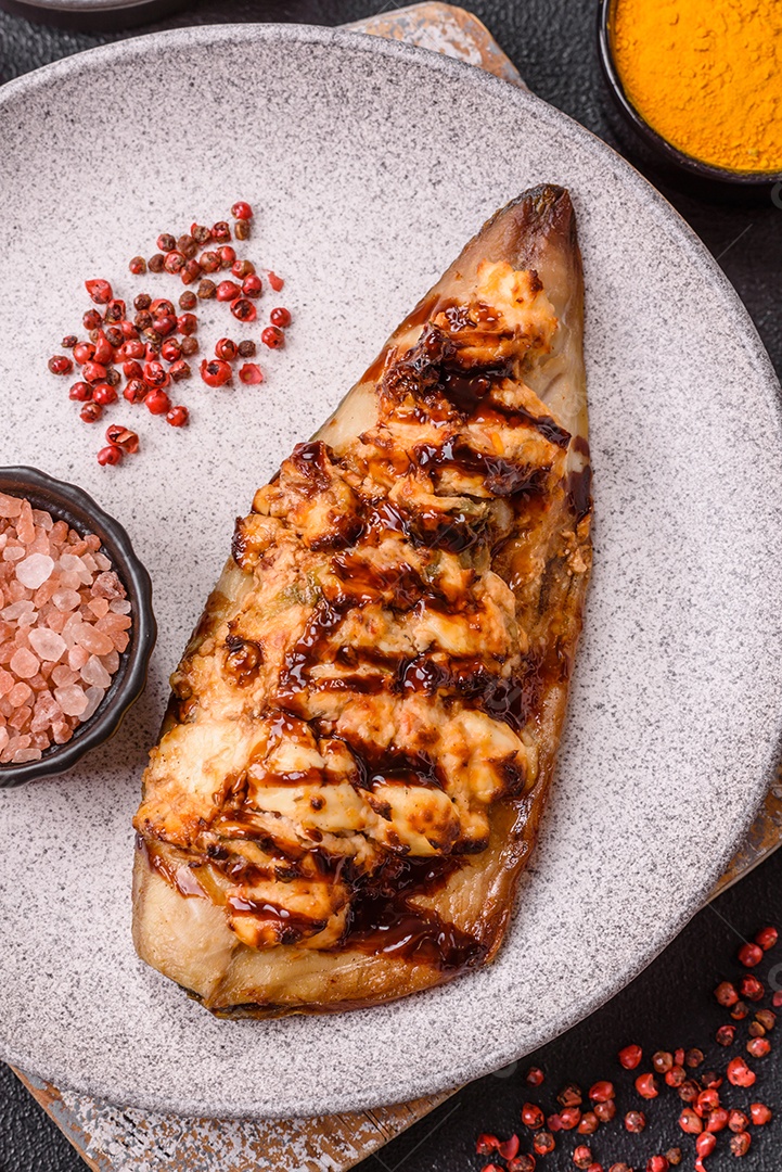 O prato na imagem parece ser um filé de cavala grelhado, servido com um molho e pimenta rosa.