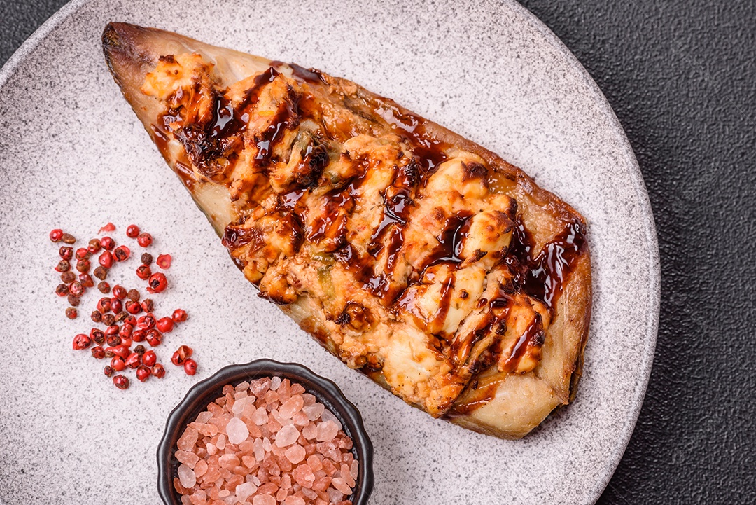 O prato na imagem parece ser um filé de cavala grelhado, servido com um molho e pimenta rosa.