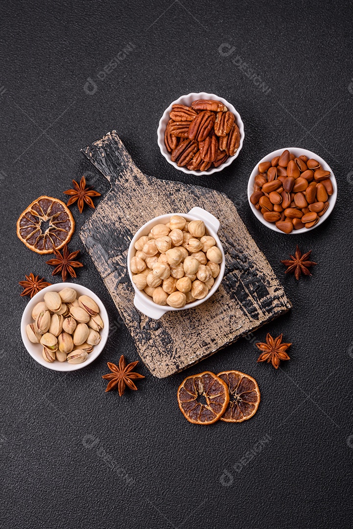 A imagem mostra uma variedade de nozes e frutas secas dispostas sobre uma tábua de madeira e um fundo escuro.