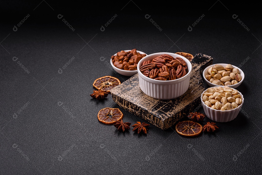 A imagem mostra uma variedade de nozes e frutas secas dispostas sobre uma tábua de madeira e um fundo escuro.