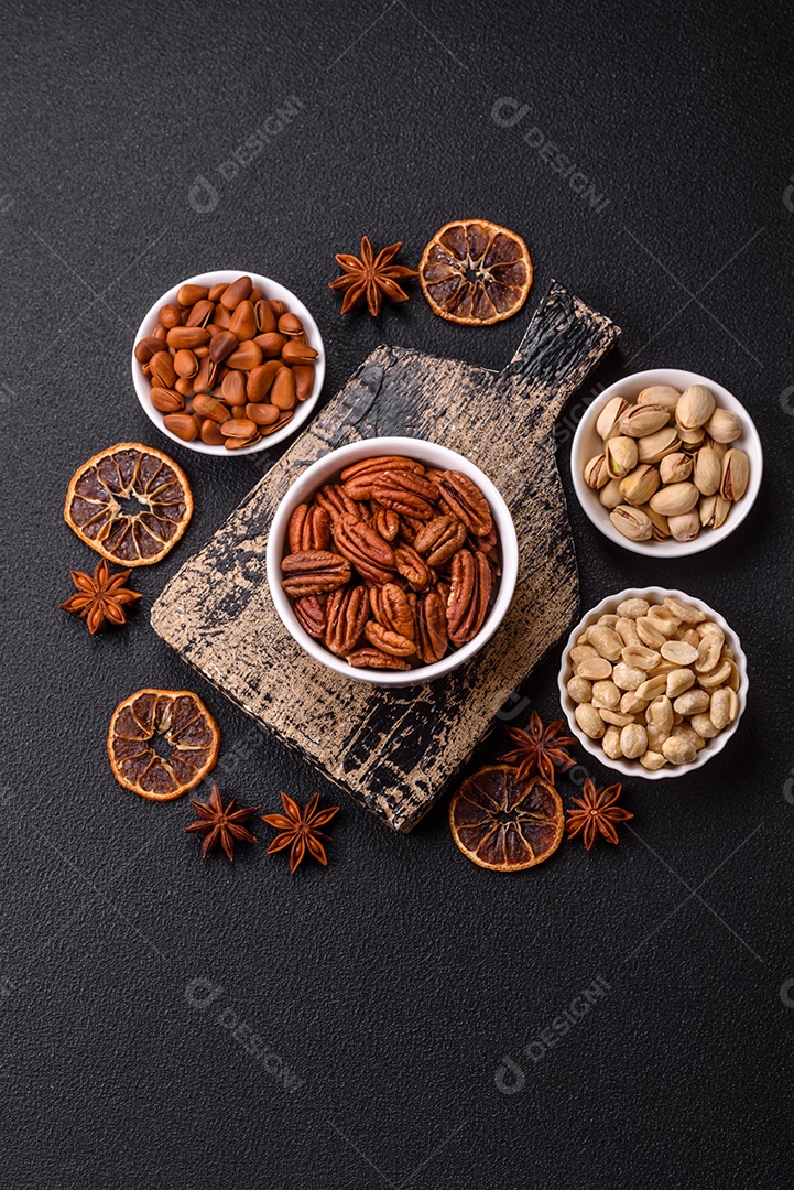 A imagem mostra uma variedade de nozes e frutas secas dispostas sobre uma tábua de madeira e um fundo escuro.