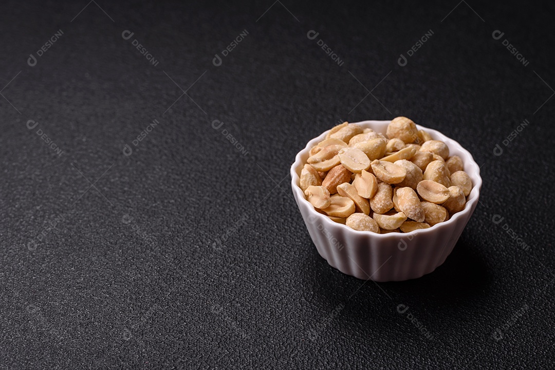 A imagem mostra uma variedade de nozes e frutas secas dispostas sobre uma tábua de madeira e um fundo escuro.