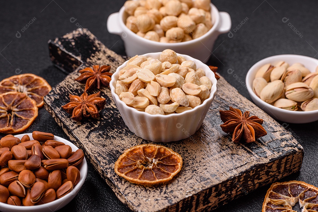 A imagem mostra uma variedade de nozes e frutas secas dispostas sobre uma tábua de madeira e um fundo escuro.
