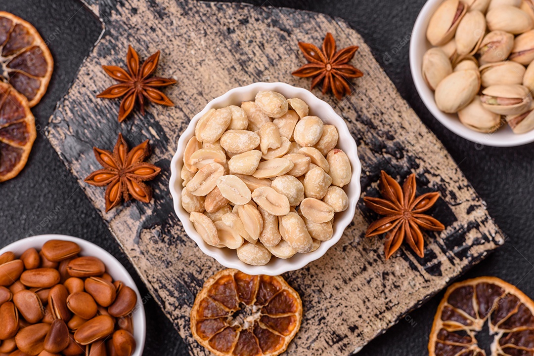A imagem mostra uma variedade de nozes e frutas secas dispostas sobre uma tábua de madeira e um fundo escuro.