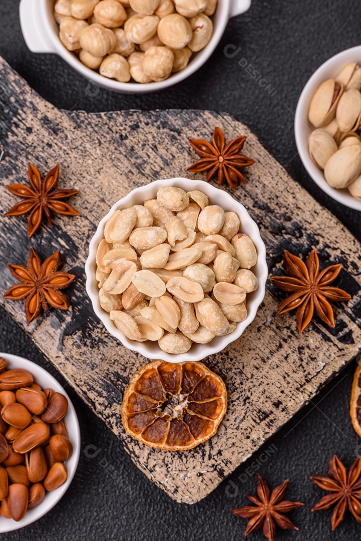 A imagem mostra uma variedade de nozes e frutas secas dispostas sobre uma tábua de madeira e um fundo escuro.