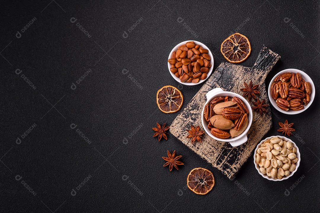 A imagem mostra uma variedade de nozes e frutas secas dispostas sobre uma tábua de madeira e um fundo escuro.
