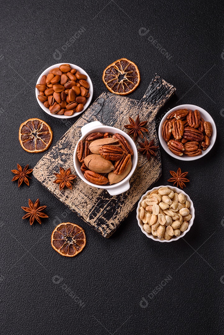 A imagem mostra uma variedade de nozes e frutas secas dispostas sobre uma tábua de madeira e um fundo escuro.