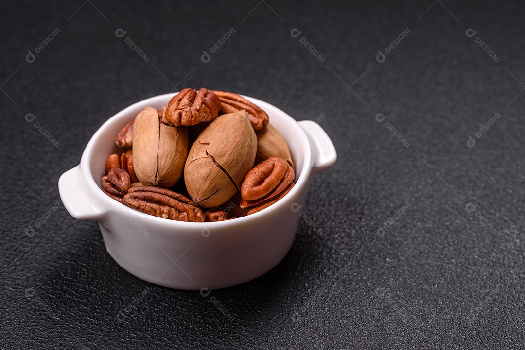A imagem mostra uma variedade de nozes e frutas secas dispostas sobre uma tábua de madeira e um fundo escuro.