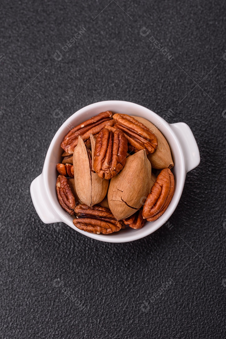 A imagem mostra uma variedade de nozes e frutas secas dispostas sobre uma tábua de madeira e um fundo escuro.