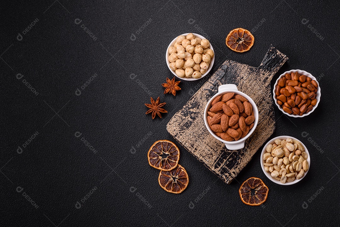 A imagem mostra uma variedade de nozes e frutas secas dispostas sobre uma tábua de madeira e um fundo escuro.