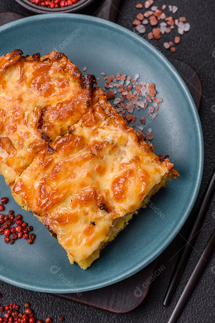 A imagem mostra um prato de lasanha com tomate cereja e pimenta rosa em grão