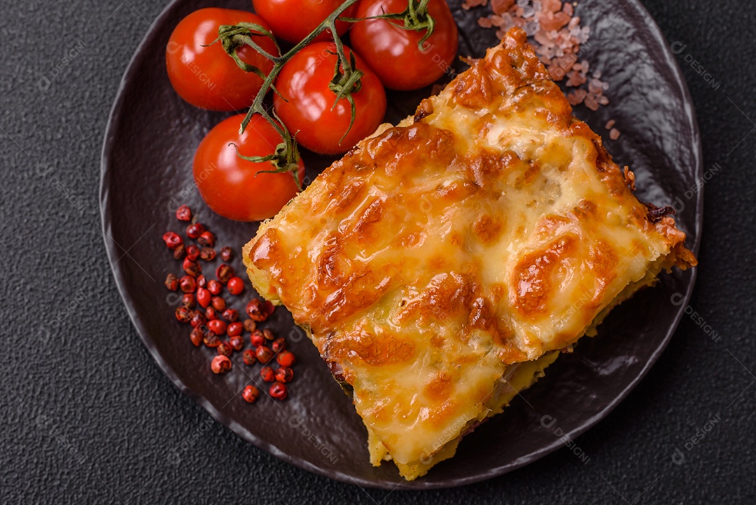A imagem mostra um prato de lasanha com tomate cereja e pimenta rosa em grão