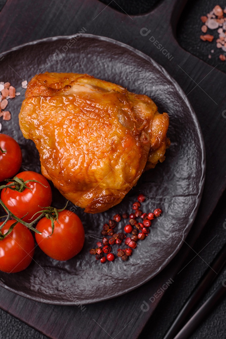 A imagem mostra sobrecoxa de frango assada, acompanhada de tomate cereja em rama e sal grosso.