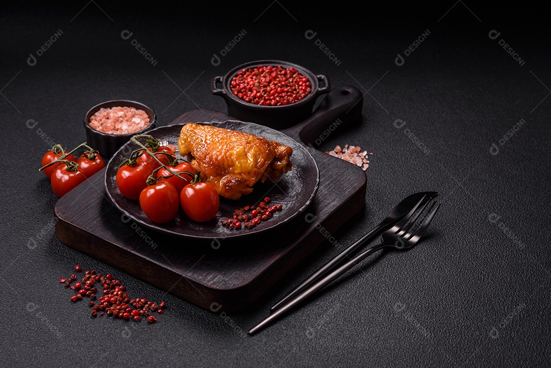 A imagem mostra sobrecoxa de frango assada, acompanhada de tomate cereja em rama e sal grosso.