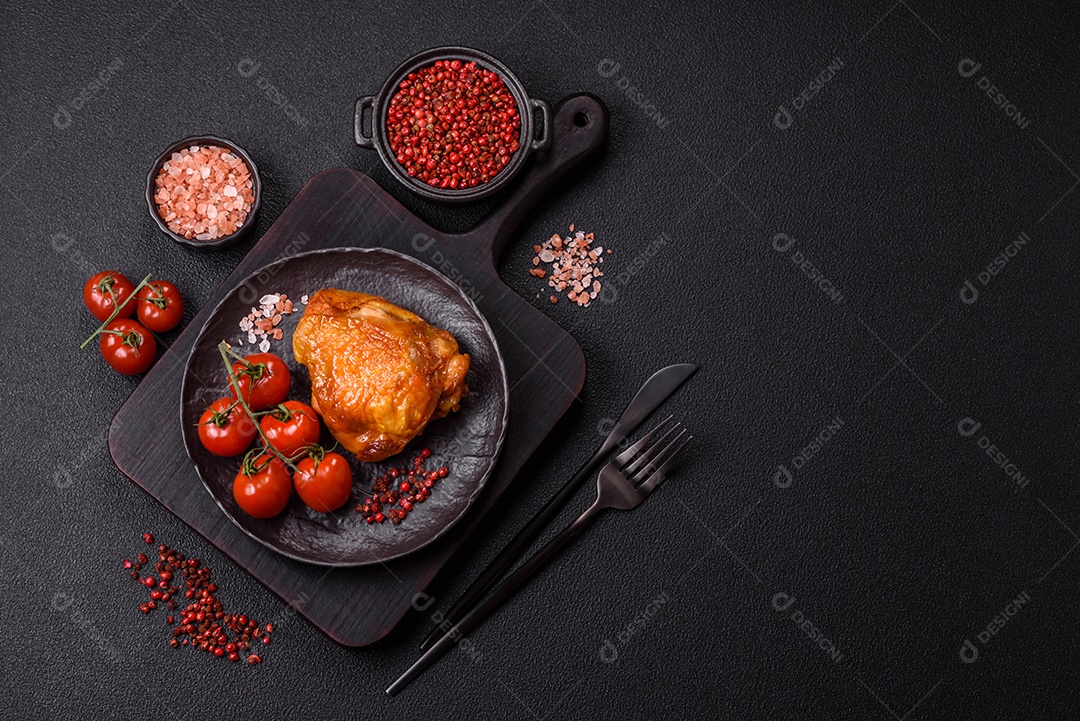 A imagem mostra sobrecoxa de frango assada, acompanhada de tomate cereja em rama e sal grosso.