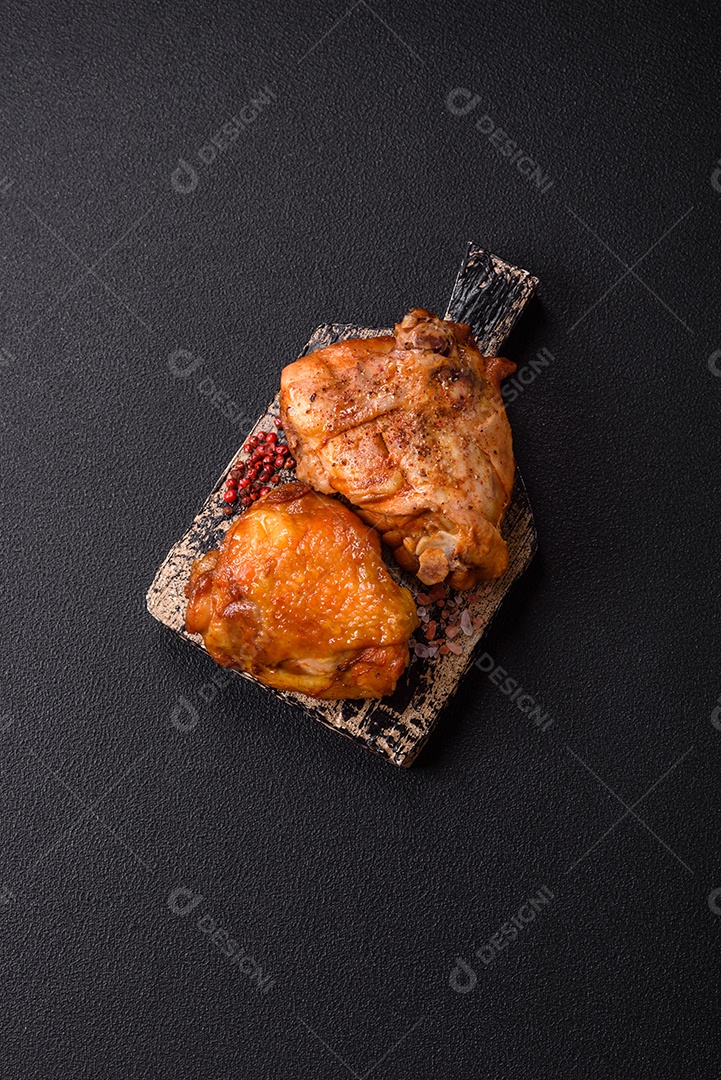 A imagem mostra sobrecoxa de frango assada, acompanhada de tomate cereja em rama e sal grosso.