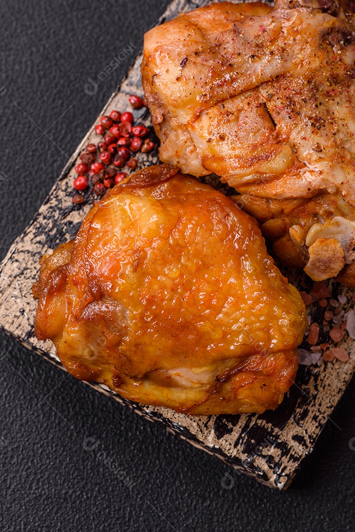 A imagem mostra sobrecoxa de frango assada, acompanhada de tomate cereja em rama e sal grosso.