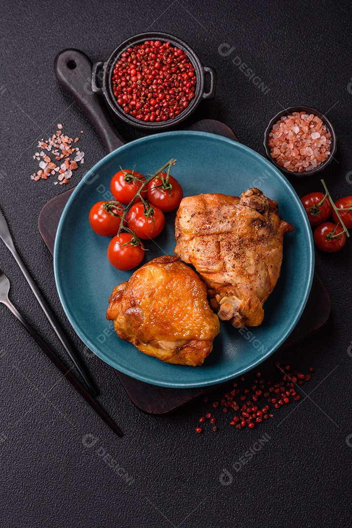 A imagem mostra sobrecoxa de frango assada, acompanhada de tomate cereja em rama e sal grosso.