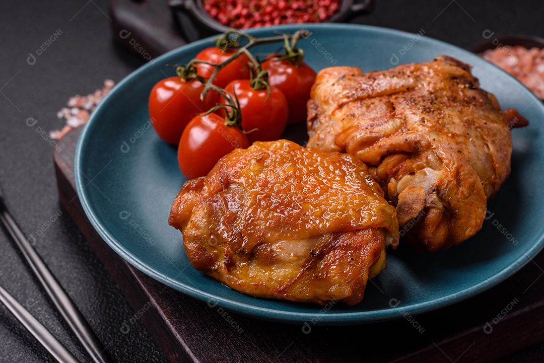 A imagem mostra sobrecoxa de frango assada, acompanhada de tomate cereja em rama e sal grosso.