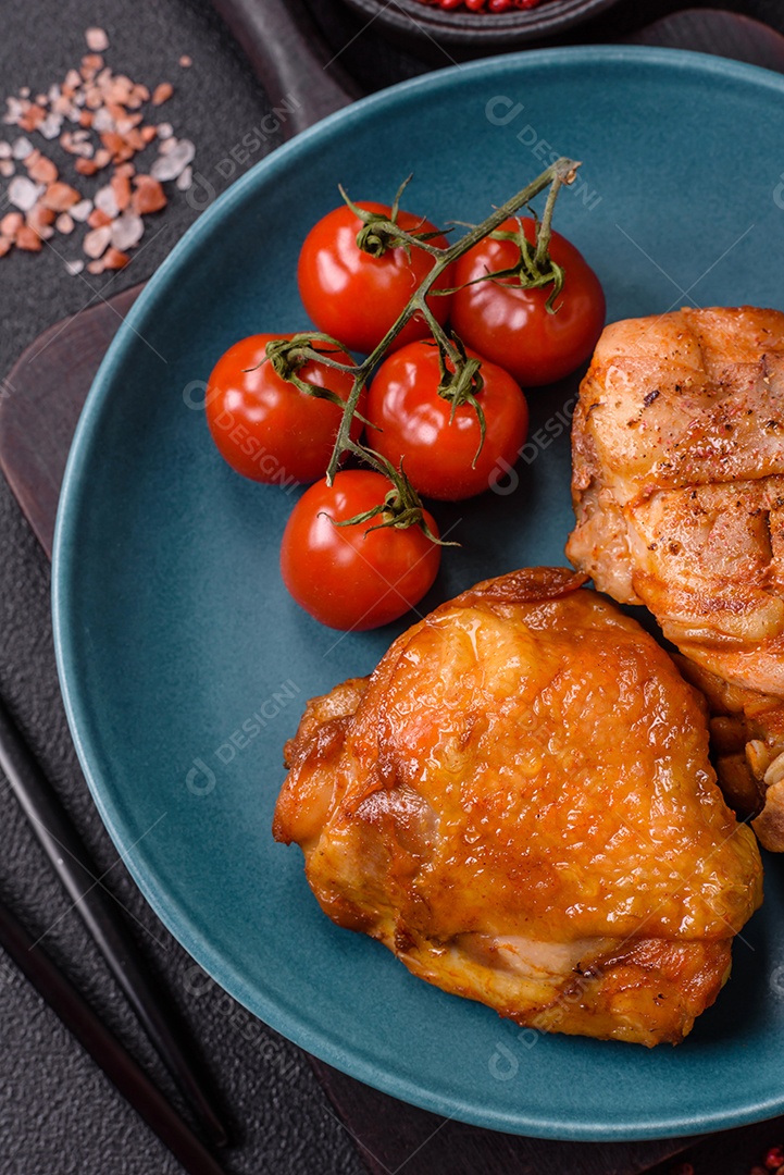 A imagem mostra sobrecoxa de frango assada, acompanhada de tomate cereja em rama e sal grosso.