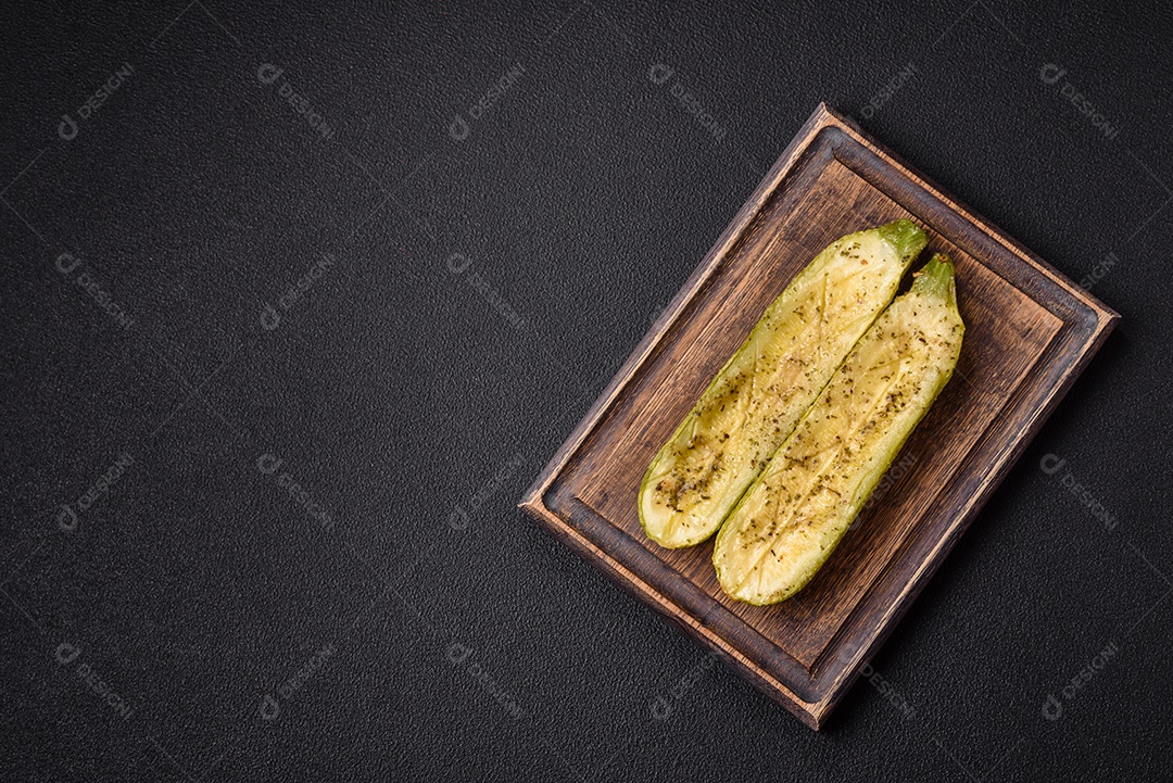 A imagem mostra uma abobrinha italiana assada ou grelhada, servida em um prato com tomate cereja e temperos
