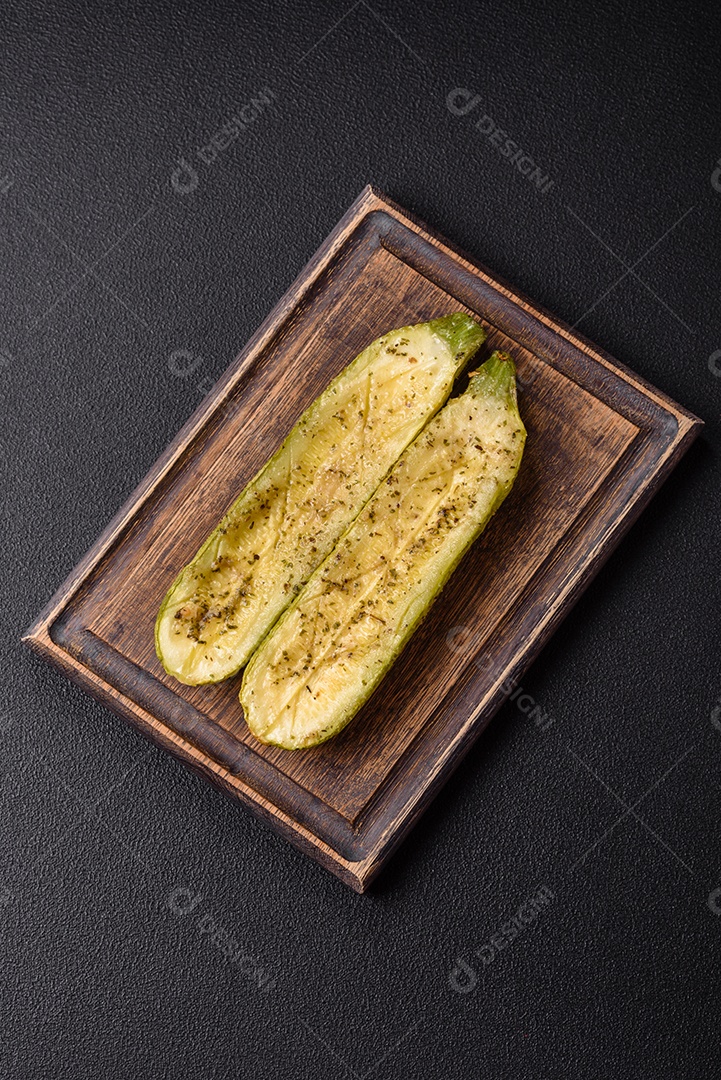 A imagem mostra uma abobrinha italiana assada ou grelhada, servida em um prato com tomate cereja e temperos