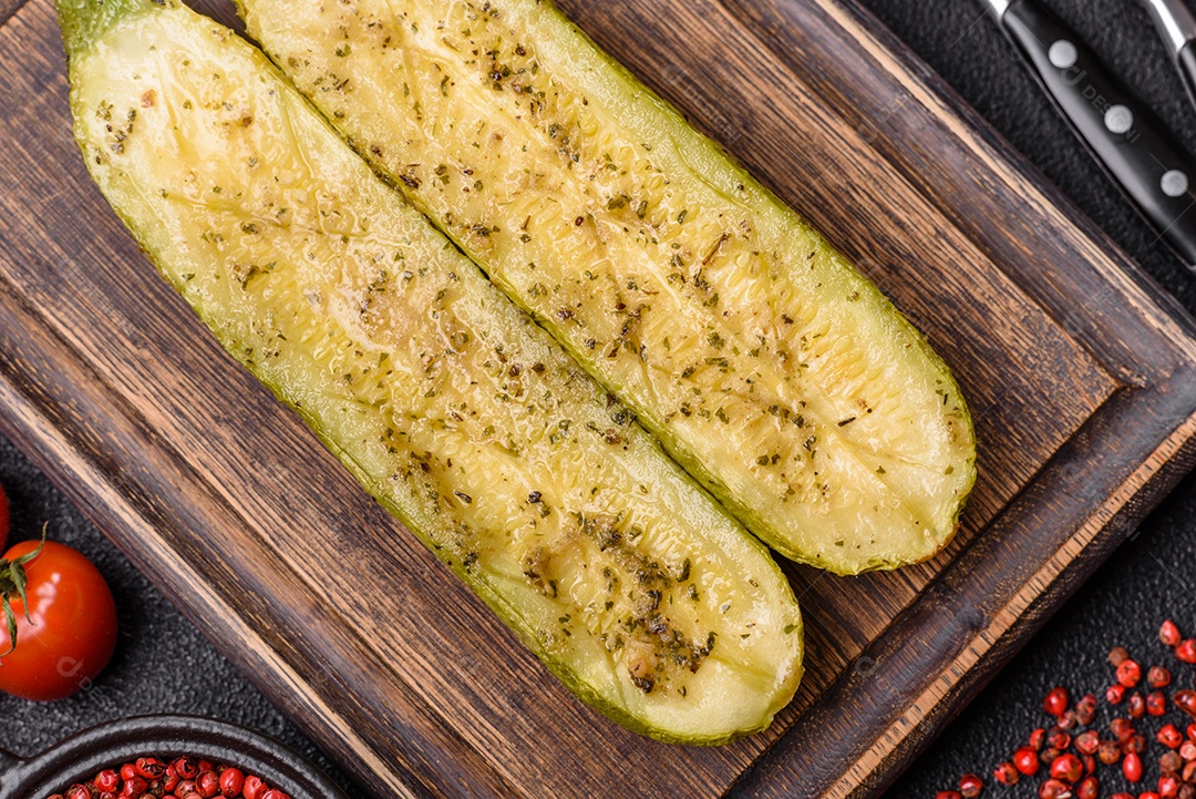 A imagem mostra uma abobrinha italiana assada ou grelhada, servida em um prato com tomate cereja e temperos