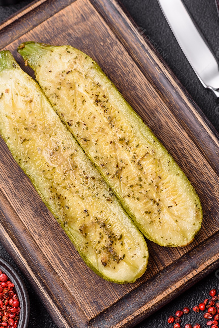 A imagem mostra uma abobrinha italiana assada ou grelhada, servida em um prato com tomate cereja e temperos
